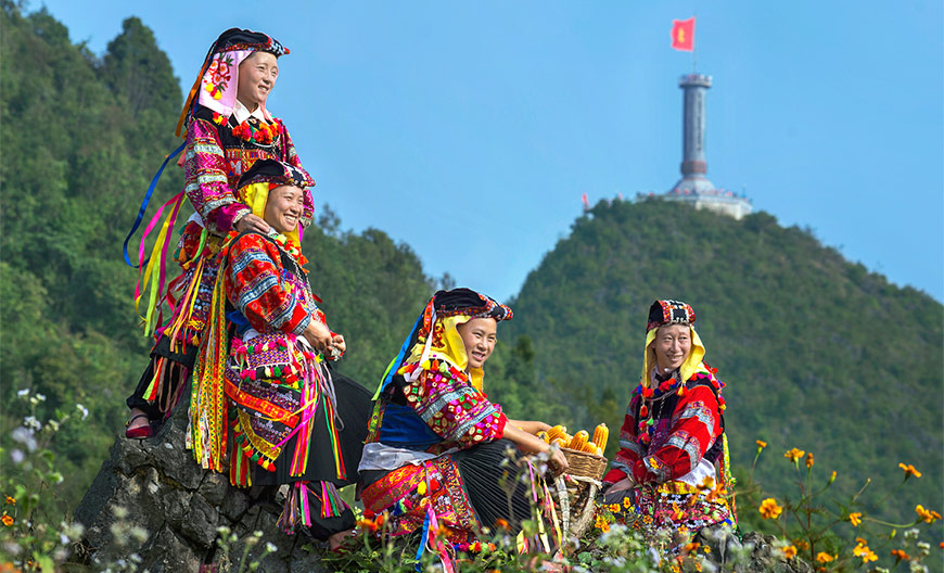 Women from the Lolo ethnic minority sitting in front of the Lung Cu Flag Tower, highest point in Northern Vietnam